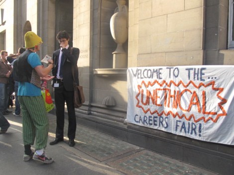 Students by banner reading "Welcome to the unethical careers fair"