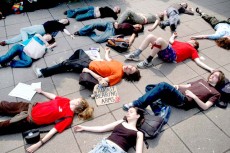 Students lie on the ground as if dead. Teddy bear lies with banner saying 'against bearing arms'