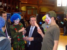 Protesters dressed as clowns talk to staff at a careers fair