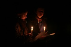 Two students holding candles and papers at a candlelit vigil